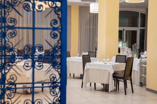 a dining room with white tables and chairs and a gate at Club Azzurro Hotel & Resort in Porto Cesareo