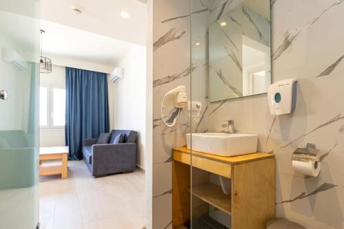 bagno con lavandino e specchio di Aqua Luxury Suites by Estia a Roda