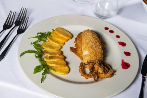 a white plate with chicken and vegetables on a table at Club Azzurro Hotel & Resort in Porto Cesareo