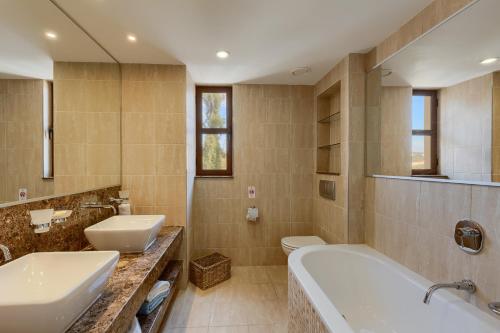 a bathroom with two sinks and a tub and a toilet at Aphrodite Hills Rentals - Apartments in Kouklia