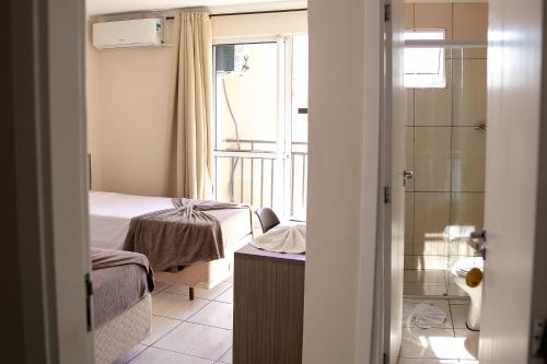 a small bedroom with a bed and a shower at Royal Trip Hotel in Guarapuava