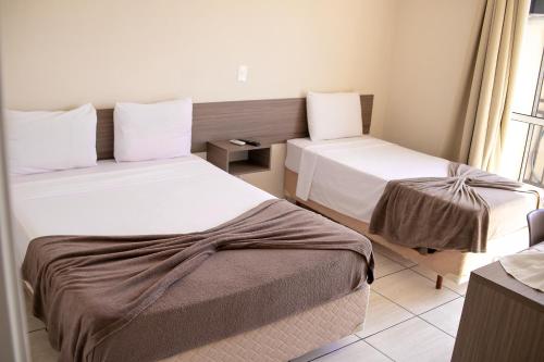 a hotel room with two beds and a window at Royal Trip Hotel in Guarapuava