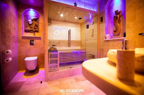 La salle de bains est pourvue de toilettes et d'une douche avec un éclairage violet. dans l'établissement Loveroom La Garçonn'Hyeres, à Hyères