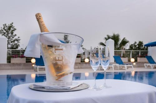 a table with two wine glasses and a bottle on it at Club Azzurro Hotel & Resort in Porto Cesareo