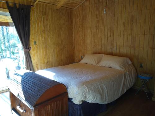een slaapkamer met een bed in een houten muur bij Cabaña entre Arboles in Villarrica