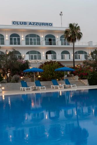 a pool with chairs and umbrellas in front of a hotel at Club Azzurro Hotel & Resort in Porto Cesareo