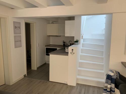 a kitchen with white cabinets and a staircase with a window at Ostsee Ferienwohnung Möwengasse in Travemünde