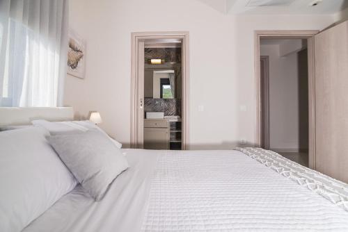 a white bedroom with a large white bed with white pillows at Daisy's Garden - Villa with Private Pool, Ideal for Large Groups, by ZanteWize in Dhrákas