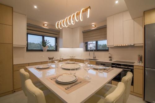 a kitchen with a dining table with chairs and a refrigerator at Daisy's Garden - Villa with Private Pool, Ideal for Large Groups, by ZanteWize in Dhrákas