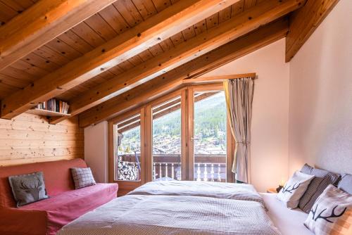 a bedroom with a bed and a large window at Dachwohnung Balma-great overview of Zermatt in Zermatt