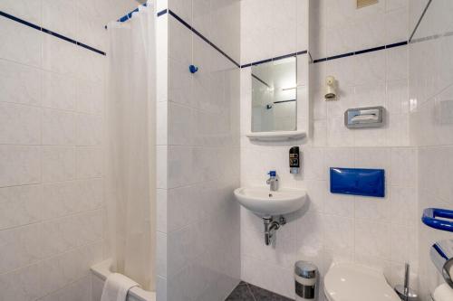 ein weißes Bad mit einem Waschbecken und einem WC in der Unterkunft a&o Berlin Kolumbus in Berlin