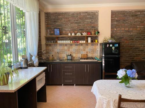 a kitchen with a black refrigerator and a brick wall at Guest house Shekvetili in Shekhvetili