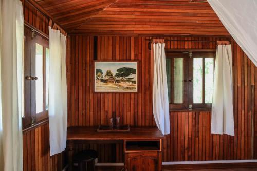 a room with wooden walls and windows with curtains at KIMONY RESORT in Morondava