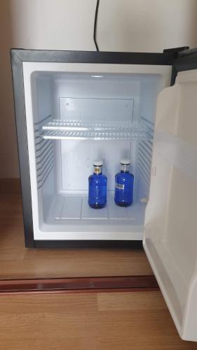 two blue bottles are sitting inside of an open refrigerator at Chambre Executive Luxe et Confort pour vos Séjours in Schweighouse-sur-Moder