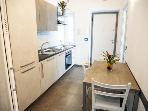 a kitchen with a table and a sink and a refrigerator at Le Casette sul Mare - Case Vacanza in Cittadella del Capo