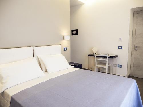 a bedroom with a bed with white sheets and a table at Le Casette sul Mare - Case Vacanza in Cittadella del Capo