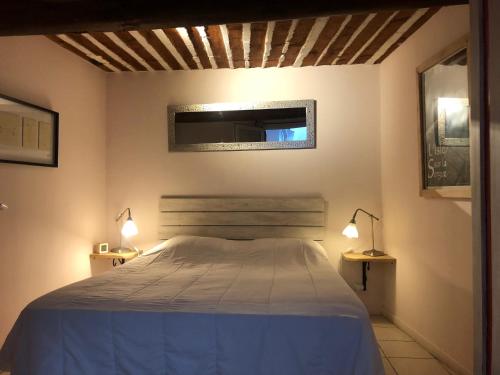 1 dormitorio con 1 cama y 2 luces en la pared en Au 10, en LʼIsle-sur-la-Sorgue