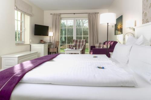 a hotel room with a large white bed and a living room at Hotel Landhaus Ellerbrock in Sankt Peter-Ording