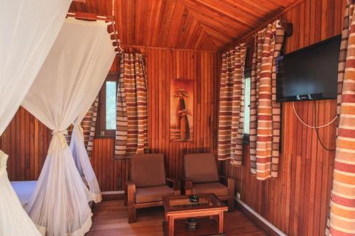 a bedroom with two chairs and a bed and a tv at KIMONY RESORT in Morondava
