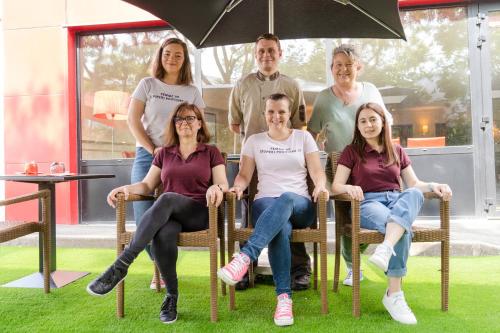 a group of people sitting in chairs under an umbrella at Brit Hotel Essentiel Cholet in Cholet