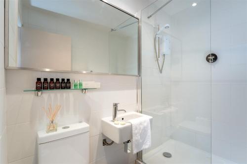 a white bathroom with a sink and a shower at Palm Grove Apartments in Torquay