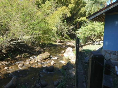 a creek next to a house with a fence at Casa do Artista in Lumiar