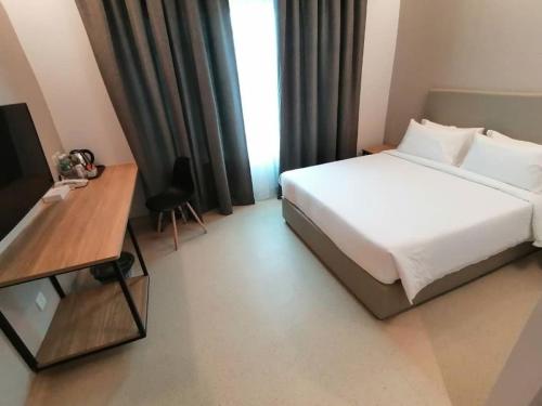 a bedroom with a bed and a desk and a television at Serapi Verdure Hotel in Kuching