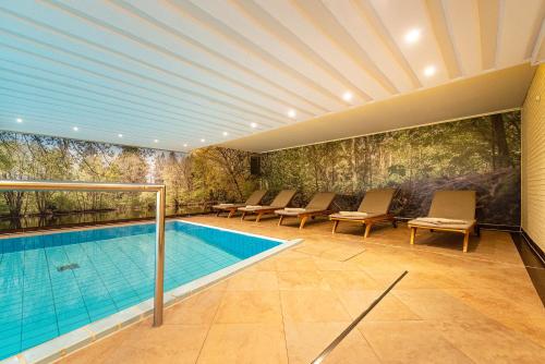 a swimming pool with chairs and a painting on the wall at Hotel Munte am Stadtwald in Bremen