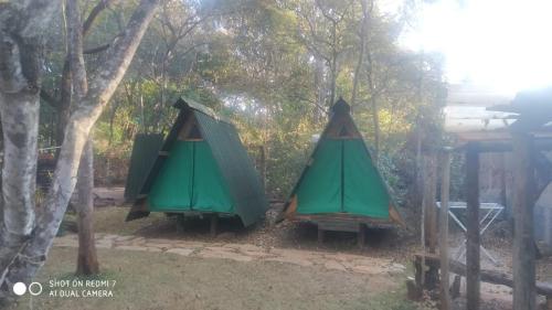 a couple of green tents hanging from trees at Recanto da Filó Serra do Cipó in Serra do Cipo