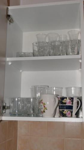 a shelf with glasses and a cupboard filled with dishes at Warmińskie Mieszkanko in Biskupiec