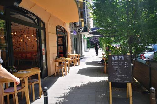 a sidewalk with tables and chairs outside of a restaurant at FilinHome Pionirska Parkview Suite in Novi Sad