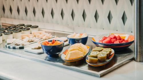 Una línea de buffet con tazones de fruta y otros alimentos. en One Shot Reina Victoria, en Valencia