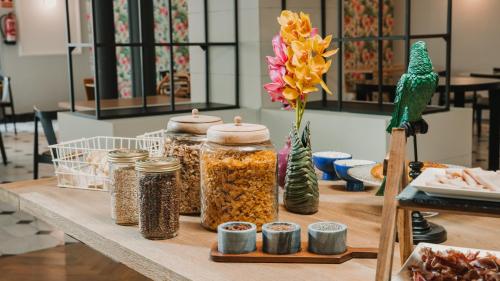 Una mesa con frascos de comida y un jarrón con una flor. en One Shot Reina Victoria, en Valencia