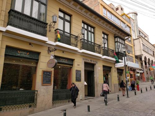 a woman walking down a street in front of a building at Hotel Naira in La Paz