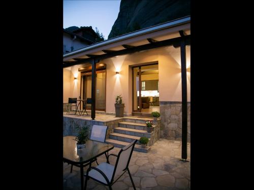 a house with a patio with a table and chairs at Under the rocks meteora panoramic view villa in Kalabaka
