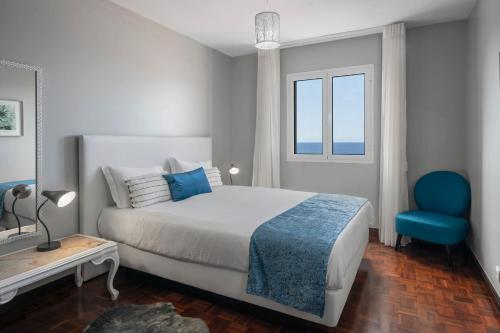 een slaapkamer met een bed en een blauwe stoel bij Alegria III by An Island Apart in Funchal