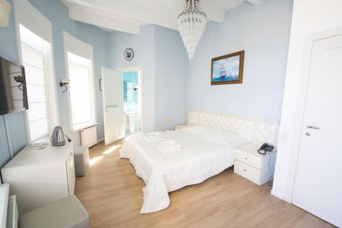 a white bedroom with a bed and a television at Kolyada Hotel in Odesa