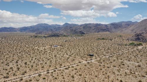 an aerial view of a field with mountains in the background at @ Marbella Lane - The Moon Designer Home right behind the JTNP in Joshua Tree