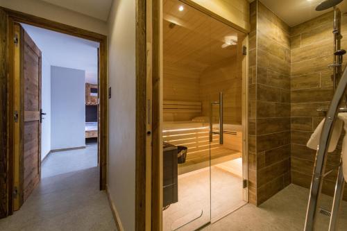 a bathroom with a walk in shower and a glass door at CAPRICORNE - Chalet sur les pistes avec sauna et home cinema in La Toussuire