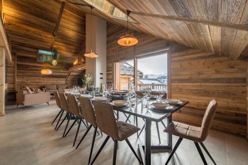 une salle à manger avec une longue table et des chaises dans l'établissement CAPRICORNE - Chalet sur les pistes avec sauna et home cinema, à La Toussuire