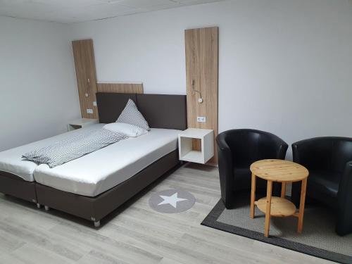 a bedroom with a bed and a chair and a table at Restaurant & Hotel Exquisite in Bobenheim am Berg