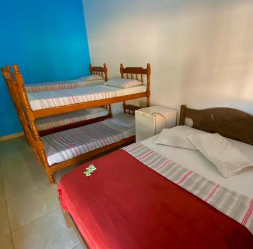a room with three beds and a red blanket at Pousada Cauna in Caraguatatuba