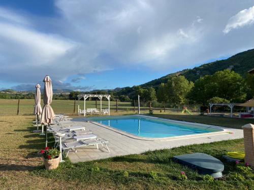 - une piscine avec des chaises et des parasols à côté dans l'établissement Casa Vacanze Garofoli, à Genga