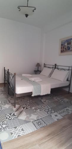 two twin beds in a room with a rug at Villa Spyros Santorini in Perissa