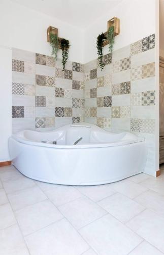 a white bath tub in a bathroom with tiles at Mama Maja in Vacri