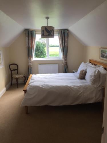 a bedroom with a large white bed and a window at Larksfield Loft in Okehampton