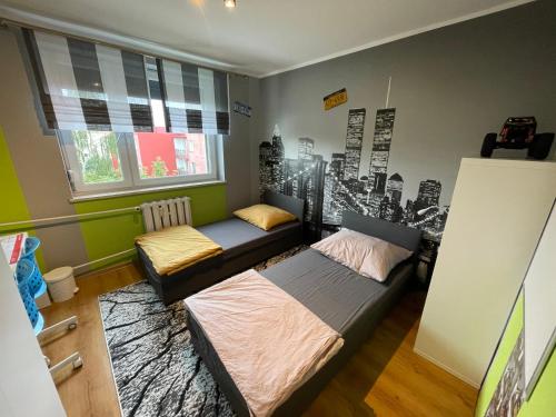 a bedroom with two beds and a city mural on the wall at Shutter Apartment in Gorzów Wielkopolski