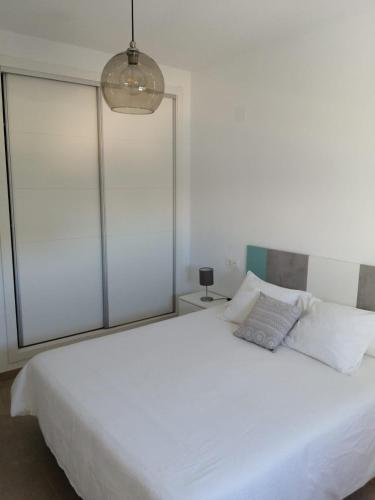 a bedroom with a large white bed and a lamp at Apartamento Carlos in Rota