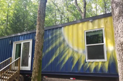 a blue and yellow tiny house between two trees at Camptel Poconos in Albrightsville