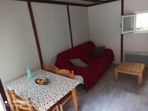 Cette petite chambre comprend une table et un canapé rouge. dans l'établissement Le pré aux sages, à Dadonville